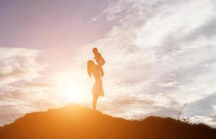 Silhouettes of mother and little daughter walking at sunset photo