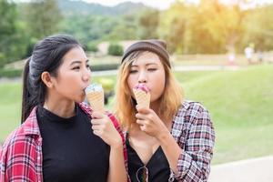 Close up shot of ice cream in hand of a woman standing with her friend. Summer holiday together. photo