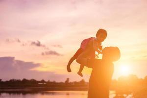 Father took the baby learn to walk at sunset. photo