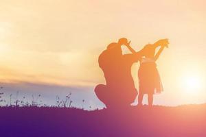 Father took the baby learn to walk at sunset. photo