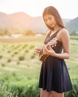 Beautiful woman holding a guitar on his shoulder, Nature park summer outside. photo