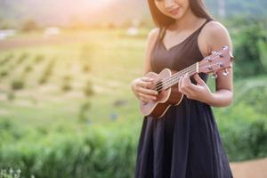 hermosa mujer sosteniendo una guitarra en su hombro, parque natural de verano afuera. foto