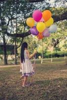 Little girl with balloons in a field photo