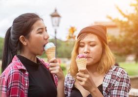 Close up shot of ice cream in hand of a woman standing with her friend. Summer holiday together. photo