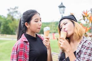 Close up shot of ice cream in hand of a woman standing with her friend. Summer holiday together. photo