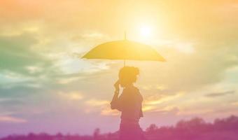 Silhouette of the beautiful girl in the nature at summer sunset. photo