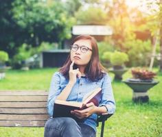 Hipster charming girl relaxing in the park while read book, Enjoy nature around. photo