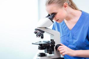 Young teen doctoral student in Medical university working study virus vaccine in school lab with microscope. photo