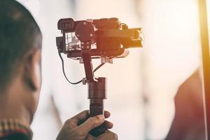 Videographer recording video with mirrorless digital camera on Gimbal Stabilization system photo