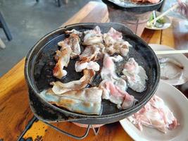 Grilled pork belly on a hot pan, on a wooden table photo