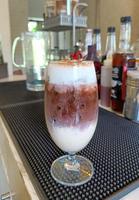 chocolate helado con espuma de leche en el vaso sobre el mostrador. concepto de propietario de cafetería de pequeña empresa, fondo borroso foto