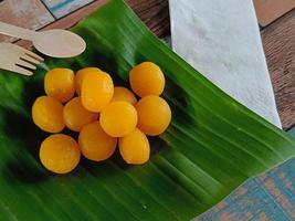 vista superior, thong yod o tarta redonda de yema de huevo, un antiguo postre tailandés, naranja y oro, tiene un sabor dulce en hoja de plátano foto