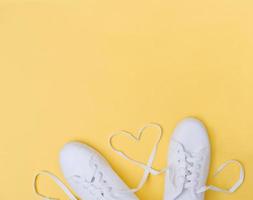 zapatillas blancas con cordones en forma de corazón sobre fondo amarillo foto