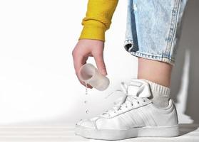 female hand pouring water on a white sneakers. photo