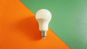 White light bulb on colored background in pastel colors. Minimalist concept, bright idea concept, isolated lamp photo