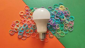 White light bulb on colored background in pastel colors. Minimalist concept, bright idea concept, isolated lamp photo