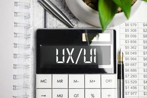 ux ui words on display calculator and pen on wooden background photo