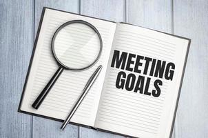 MEETING GOALS. magnifier on brown notepad text on magnifier glass photo