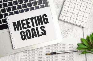 MEETING GOALS . text on white paper and laptop on wooden background photo