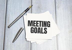 MEETING GOALS text on a sticky on notebook with pen photo
