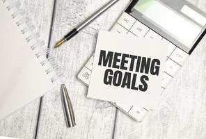 MEETING GOALS text on sticker with calculator, glasses and magnifier photo