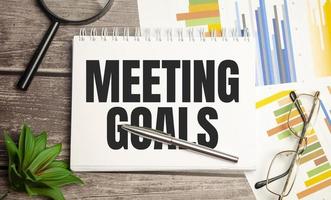 MEETING GOALS. magnifier on brown notepad text on magnifier glass photo