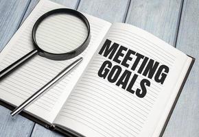 MEETING GOALS. magnifier on brown notepad text on magnifier glass photo