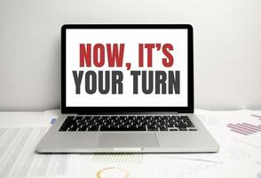 NOW ITS YOUR TURN words on laptop display and charts