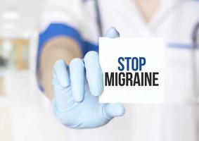 Doctor holding a card with text Stop Migraine, medical concept photo