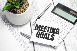 MEETING GOALS text on sticker with calculator, glasses and magnifier