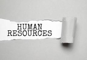 Torn grey paper on white surface with HUMAN RESOURCES word. Business concept photo