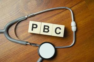 The word pbc is written on wooden cubes near a stethoscope photo