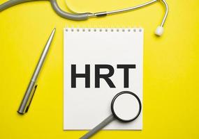 In the notebook is the text hrt and stethoscope, on yellow background photo