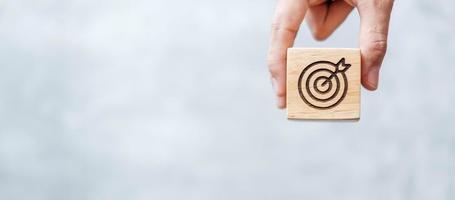 hand hold dartboard block with business goal, strategy, target, mission, action, objective, aim and success concept photo