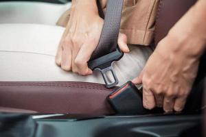 woman driver hand fastening seat belt during sitting inside a car and driving in the road. safety, trip, journey and transport concept photo