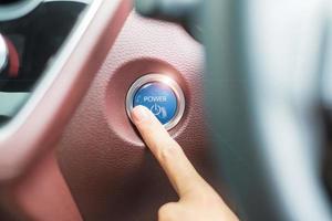 Finger press a car ignition button or START engine inside modern electric automobile. Keyless, change, strategy, vision, innovation and future concept photo