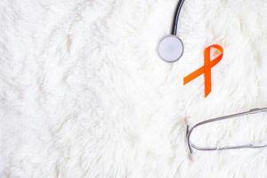 Leukemia, Kidney cancer day, world Multiple Sclerosis, CRPS, Self Injury Awareness month, Orange Ribbon with stethoscope for support people living and illness. Healthcare and World cancer day concept photo