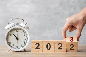 feliz año nuevo con reloj despertador vintage y cambio manual de 2022 a bloque 2023. concepto de navidad, nuevo comienzo, resolución, cuenta regresiva, metas, plan, acción y motivación foto