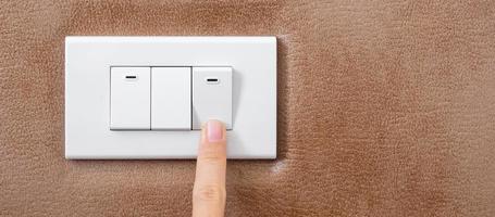 finger turn on or off on light switch on wall at home. Energy Saving, power, electrical and lifestyle concepts photo