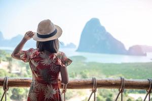 Happy traveler woman enjoy Phang Nga bay view point, alone Tourist relaxing at Samet Nang She, near Phuket in Southern Thailand. Southeast Asia travel, trip and summer vacation concept photo