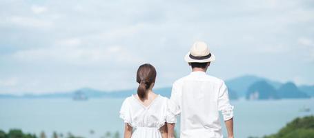 Happy couple traveler in white shirt and dress enjoy Beautiful view, Tourists with standing and relaxing over ocean. travel, together, love, summer and vacation concept photo