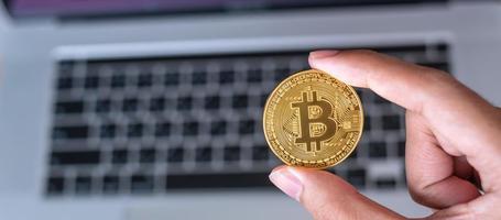 Businessman hand holding golden Bitcoin  cryptocurrency over laptop keyboard, Crypto is Digital Money within the blockchain network, is exchanged using technology and online exchange concept photo