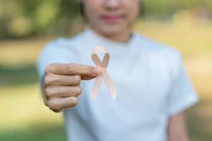 September Uterine Cancer Awareness month, woman hand holding Peach Ribbon for supporting people living and illness. Healthcare and World cancer day concept photo