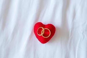 decoración en forma de corazón y anillo de compromiso de pareja dorado sobre fondo blanco. concepto de amor, juntos y feliz día de san valentín foto