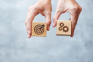 hand hold dartboard and gear block with business goal, strategy, target, mission, action, objective, aim and success concept photo