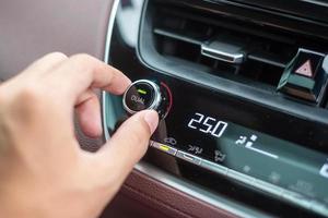 man hand adjusting temperature the air flowing during driving car on the road, air conditioner cooling system inside the car. Adjust, temperature and transport concept photo