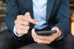 young Businessman in suit holding and using smartphone for sms messages, man typing touchscreen mobile phone in office or cafe. business, lifestyle, technology and Social media network concept photo