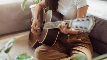 Woman playing guitar at home. Beautiful woman smiling and playing guitar with her plants in living room. photo