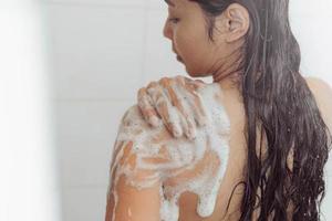 mujer joven lavando el cuerpo en la ducha. mujer asiática tomar un baño en el baño. foto