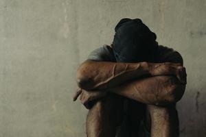 A drug addicted homeless man sitting alone and depressed in an abandoned house feeling anxious and lonely. photo